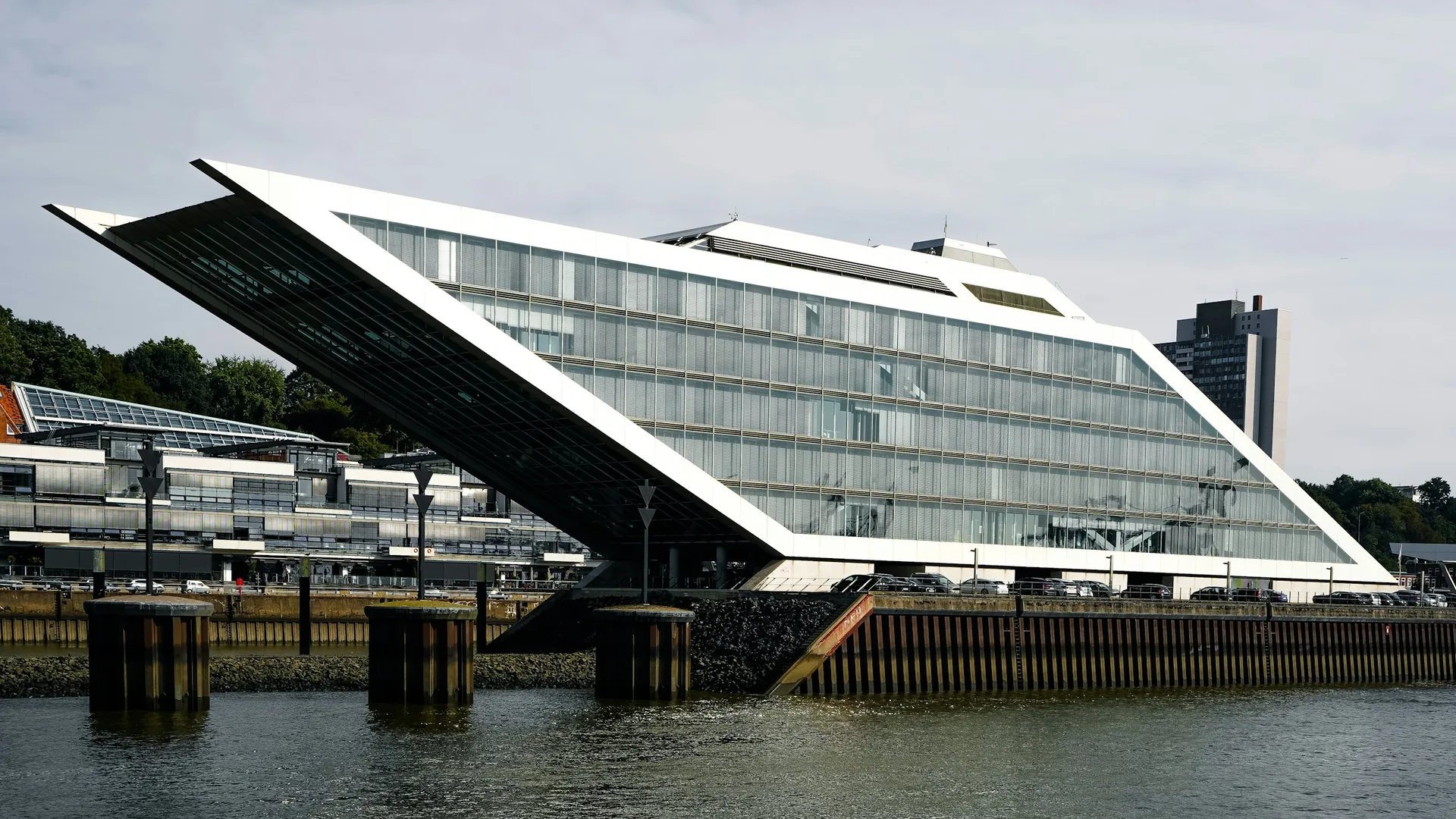 Angular glass-fronted commercial building beside a waterfront.